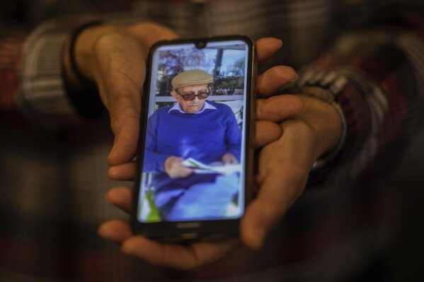 In this Monday, May 18, 2020 photo, Elena Valero shows a picture of her father Alonso Valero, 96, in Madrid, Spain. Alonso Valero was one of the residents at the Usera Center for the Elderly, who died during the coronavirus outbreak in Spain. This month, dozens of relatives of those who died in 15 Madrid nursing homes, sued the regional government and the directors of their respective nursing homes, accusing them of reckless homicide, degrading treatment, abuse of power and denial of help.  Several plaintiffs were families who had loved-ones in Usera, including Elena Valero, whose father died of COVID-19 and whose mother recovered from it.  (AP Photo/Bernat Armangue)