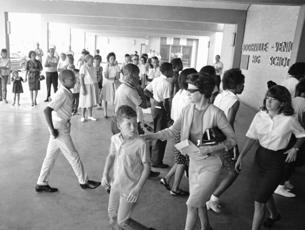 A white mother walks with her son past a group of African American students arriving for classes at formerly all-white Boothville Venice High School on Monday, Sept. 12, 1966 as racial barriers fell in Plaquemines Parish. (AP Photo/Jack Thornell, file)