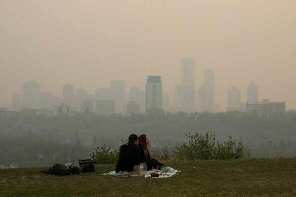 Smoke from wildfires blankets the city as a couple has a picnic in Edmonton, Alberta, Saturday, May 11, 2024. (Jason Franson/The Canadian Press via AP)