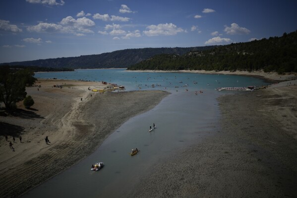 People enjoy water activities on the Lake of Sainte-Croix, southern France, as the water level continued to decline, Tuesday, Aug. 9, 2022. (AP Photo/Daniel Cole)