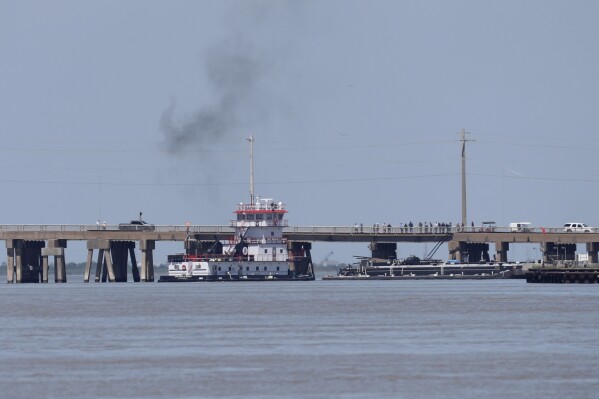 A tugboat works to maneuver a barge away from the Pelican Island Bridge in Galveston, Texas, on Wednesday, May 15, 2024, after the barge crashed into the bridge shutting down the only road access to and from the island. (Jennifer Reynolds/The Galveston County Daily News via AP)