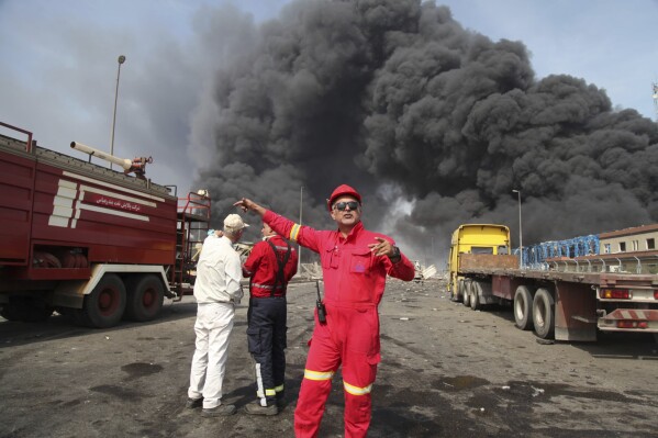In this photo provided by Islamic Republic News Agency (IRNA) firefighters work as black smoke rises in the sky after a massive explosion rocked a port near the southern city of Bandar Abbas, Iran, Saturday, April 26, 2025. (Mohammad Rasoul Moradi/IRNA via AP)