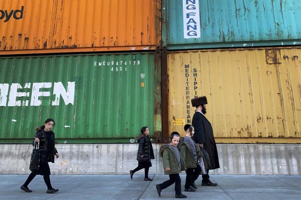 FILE - In this Tuesday, March 30, 2021 file photo, members of the Orthodox Jewish community walk past shipping containers in the South Williamsburg neighborhood of Brooklyn, New York. A comprehensive new survey of Jewish Americans finds them increasingly worried about antisemitism and sharply divided about the importance of religious observance in their lives. The wide-ranging survey, released on Tuesday, May 11, 2021, was conducted by the Pew Research Center. (AP Photo/Wong Maye-E)