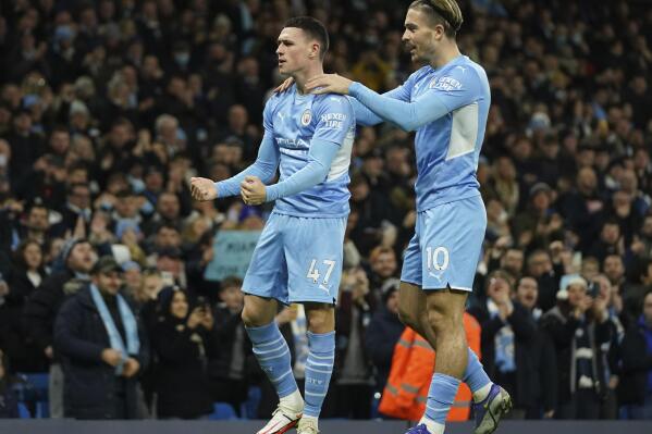 Manchester City's Phil Foden celebrates with Manchester City's Jack Grealish, right, after scoring his side's opening goal during the English Premier League soccer match between Manchester City and Leeds United at Etihad stadium in Manchester, England, Tuesday, Dec. 14, 2021. (AP Photo/Jon Super)