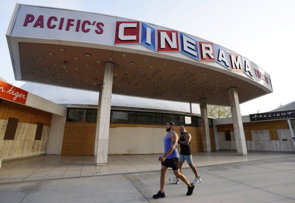 Pedestrians walk past the boarded up and closed Cinerama Dome movie theater, Monday, April 12, 2021, in Los Angeles. Pacific Theaters, which operates some 300 screens in California, including the b...