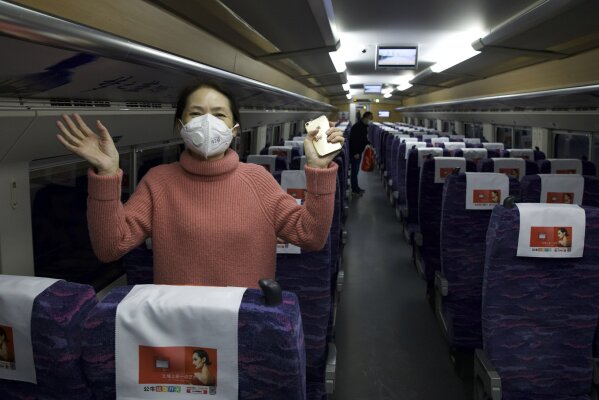 A passenger wearing a face mask to protect against the spread of new coronavirus talks about how happy she is to leave her 76-day stay in lockdown in Wuhan as she boards the first high-speed train to leave Hankou train station after the resumption of train services in Wuhan in central China's Hubei Province, Wednesday, April 8, 2020. After 11 weeks of lockdown, the first train departed Wednesday morning from a re-opened Wuhan, the origin point for the coronavirus pandemic, as residents once again were allowed to travel in and out of the sprawling central Chinese city. (AP Photo/Ng Han Guan)