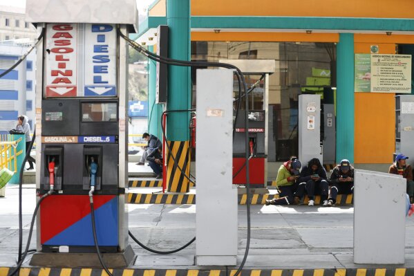 Workers sit at a gas station in La Paz, Bolivia, Thursday, Nov. 14, 2019. Gas stations have run out of fuel as the result of followers of former President Evo Morales blocking the main highway. (AP Photo/Natacha Pisarenko)