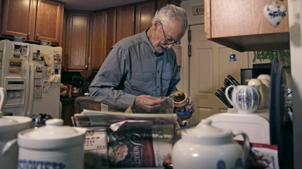 In this Nov. 22, 2019, photo, Charles Flagg, who is stricken with Alzheimer's disease, makes a peanut butter sandwich for lunch at his family home in Jamestown, R.I. Flagg is participating in a study on the drug Aducanumab. New results were released on the experimental medicine whose maker claims it can slow the decline of Alzheimer's disease, the most common form of dementia. (AP Photo/Charles Krupa)