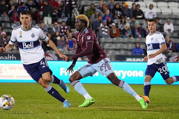Colorado Rapids forward Gyasi Zardes, center, pursues the ball between Vancouver Whitecaps defender Ranko Veselinović, left, and midfielder Andrés Cubas during the first half of an MLS soccer match Saturday, Sept. 10, 2022, in Commerce City, Colo. (AP Photo/Bart Young)