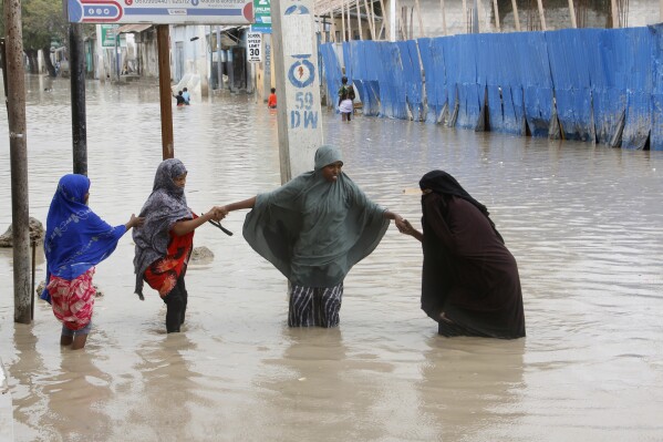 Women walk through flood water after heavy rainfall, in Mogadishu Somalia, Monday, Nov. 20, 2023. (AP Photo/Farah Abdi Warsameh)