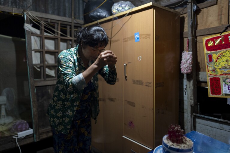 Nguyen Thi Thuy offers prayers with incense at an altar on her houseboat before beginning her day in Can Tho, Vietnam, Wednesday, Jan. 17, 2024. Unable to afford rent on land, the small family has lived on a small houseboat ever since. (AP Photo/Jae C. Hong)