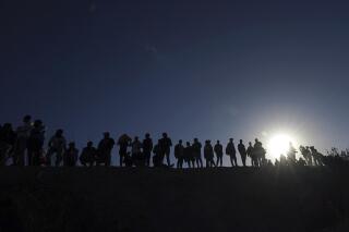 FILE - Migrants stand on the Mexican side of the U.S.-Mexico border, on the banks of the Rio Grande, in Ciudad Juarez, Mexico, March 29, 2023. About 50 migrants have been kidnapped by a gang in northern Mexico, the latest in a series of mass abductions, President Andres Manuel Lopez Obrador said Wednesday, May 17, 2023. (AP Photo/Fernando Llano, File)
