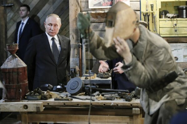 Russian President Vladimir Putin looks at a scene depicting an armament repair shop, during a visit to an exhibition -  'Memory speaks. The road through the war' in St.Petersburg, Russia, Saturday, Jan. 18, 2020. Putin attended events marking the 77th anniversary of the break of Nazi's siege of Leningrad. The Red Army broke the nearly 900-day blockade of the city on January 19, 1943 after fierce fighting. (AP Photo/Dmitri Lovetsky, Pool)