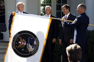 FILE - In this Aug. 29, 2019, file photo, President Donald Trump, left, watches with Vice President Mike Pence and Defense Secretary Mark Esper as the flag for U.S. space Command is unfurled as Trump announces the establishment of the U.S. Space Command in the Rose Garden of the White House in Washington. The Department of the Defense Inspector General on Friday, Feb. 19, 2021, has announced an investigation into the Trump administration's January decision to move the U.S. Space Command headquarters from Peterson Air Force Base in Colorado to the Redstone Arsenal adjacent to Huntsville, Ala. The announcement follows protests by Colorado's congressional delegation that the decision was politically motivated. (AP Photo/Carolyn Kaster, File)