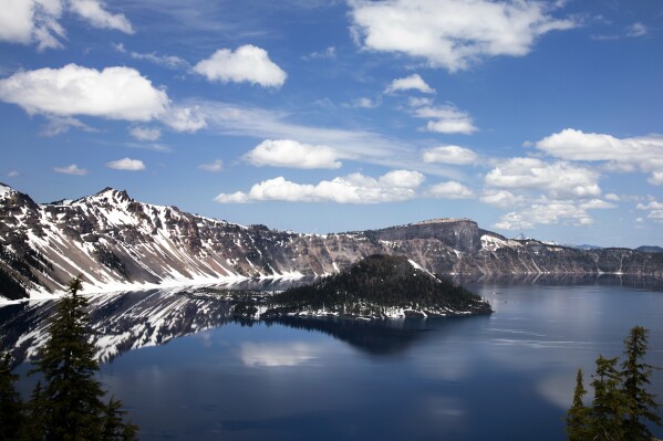 Clouds appear over Crater Lake on June 1, 2023, in Crater Lake, Ore. Management issues at Oregon's Crater Lake have prompted the federal government to consider terminating its contract with the national park's concessionaire. Crater Lake Hospitality is a subsidiary of Philadelphia-based Aramark and is contracted through 2030 to run concessions such as food and lodging. (AP Photo/Jenny Kane)