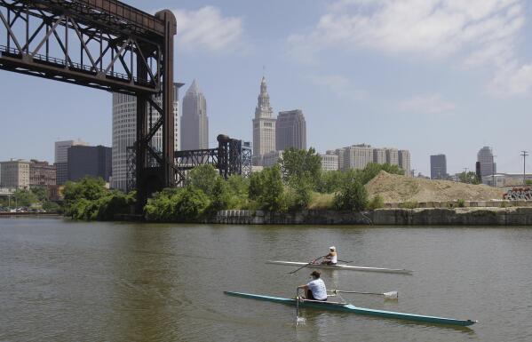 FILE – Two rowers paddle along the Cuyahoga River in Cleveland on  July 12, 2011. Tuesday, Oct. 18, 2022, is the 50th anniversary of Congress passing the Clean Water Act to protect U.S. waterways from abuses like the oily industrial pollution that caused Ohio's Cuyahoga River to catch on fire in 1969. (AP Photo/Tony Dejak, File)