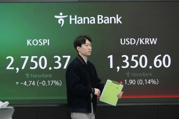 A currency trader moves by the screens showing the Korea Composite Stock Price Index (KOSPI), left, and the foreign exchange rate between U.S. dollar and South Korean won at the foreign exchange dealing room of the KEB Hana Bank headquarters in Seoul, South Korea, Thursday, March 28, 2024. Asian shares were mixed on Thursday after U.S. stocks broke out of a three-day lull to close at a record.(AP Photo/Ahn Young-joon)
