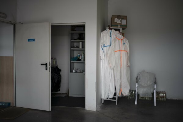 In this April 28, 2020 photo, protection suits hang in the emergency services ambulance garage in Covaleda, that responds to calls in several villages near Soria, Spain. Many in Spain's small and shrinking villages thought their low populations would protect them from the coronavirus pandemic. The opposite appears to have proved true. Soria, a north-central province that's one of the least densely peopled places in Europe, has recorded a shocking death rate. Provincial authorities calculate that at least 500 people have died since the start of the outbreak in April. (AP Photo/Felipe Dana)