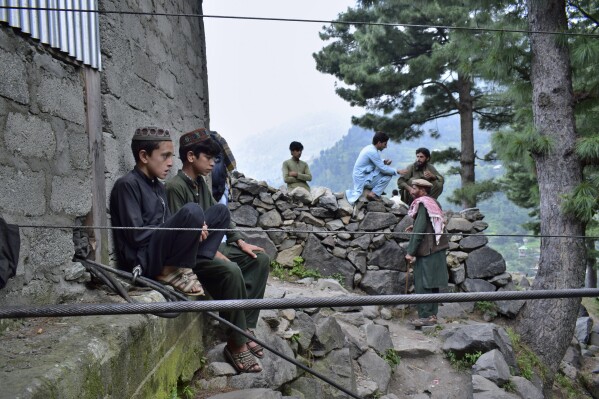 Local residents gather near the incident site, in Pashto village, a mountainous area of Battagram district in Pakistan's Khyber Pakhtunkhwa province, Wednesday, Aug. 23, 2023. The rescue of six school children and two adults who were plucked from a broken cable car that was dangling precariously hundreds of meters (yards) above a steep gorge was a miracle, a survivor said Wednesday. The teenager said he and the others felt repeatedly that death was imminent during the 16-hour ordeal. (AP Photo/Saqib Manzoor)