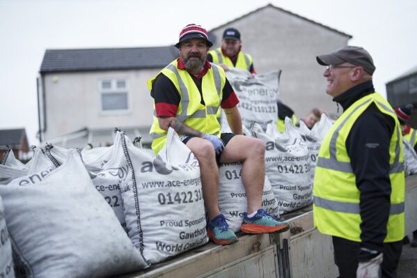 Volunteers from Ossett Rugby Club prepare to load contestants with sacks of coal during the World Coal Carrying Championships in Ossett, West Yorkshire, England, Monday, April 21, 2025. (AP Photo/Jon Super)