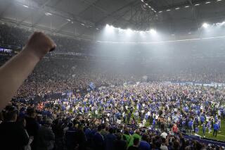 Hinchas de Schalke irrumpen en la cancha para celebrar el ascenso a la Bundesliga tras vencer 2-0 a St. Pauli, el 7 de mayo de 2022. (AP Foto/Martin Meissner)