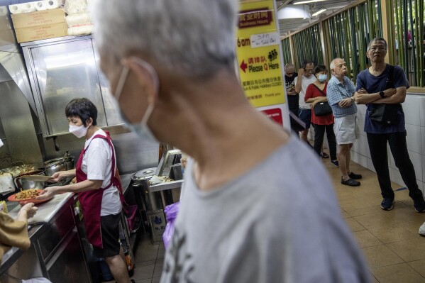 Patrons wait in line to place their order at a hawker food stall in Singapore, Monday, July 17, 2023. (AP Photo/David Goldman)