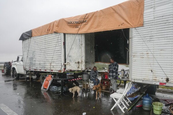 Pessoas que perderam suas casas em enchentes vivem em carreta de caminhão, sexta-feira, 10 de maio de 2024, em Canoas, Rio Grande do Sul, Brasil.  (Foto AP/André Benner)