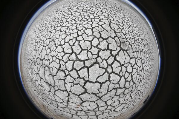 In this photograph created by a fisheye lens shows cracked mud at the Great Salt Lake on April 25, 2021, near Antelope Island, Utah. The lake in Utah has been shrinking for years, and a drought gripping the American West could make this year the worst yet. (AP Photo/Rick Bowmer)