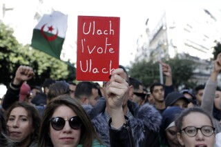 Algerian demonstrators take to the streets in the capital Algiers to reject the presidential elections, in Algeria, Dec. 12, 2019. Banner reads "Why vote, why?" (AP Photo/Toufik Doudou)