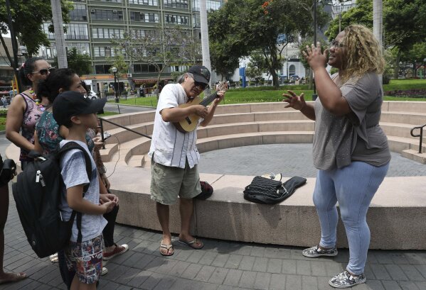
              In this Dec. 28, 2018 photo, Venezuelan singer Reymar Perdomo, right, sings with fans who approached her while she was doing a press interview at a park in the Miraflores area of Lima, Peru. According to the International Organization for Migration, more than 3 million Venezuelans have left their country since 2015 as food shortages and hyperinflation became rampant in what was once a wealthy oil-exporting nation. (AP Photo/Martin Mejia)
            