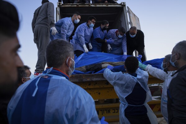 Medics unload the bodies of Palestinians killed in fighting with Israel and turned over by the Israeli military during a mass funeral in Rafah, Gaza Strip, Tuesday, Dec. 26, 2023.(AP Photo/Fatima Shbair)