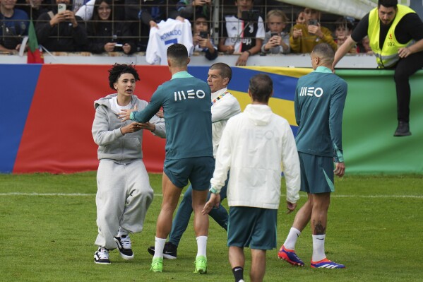 A pitch invader tries to reach Portugal's Cristiano Ronaldo during a training session in Gutersloh, Germany, Friday, June 14, 2024. Portugal will play against Czech Republic during their Group F soccer match at the Euro 2024 soccer tournament on June 18. (AP Photo/Hassan Ammar)