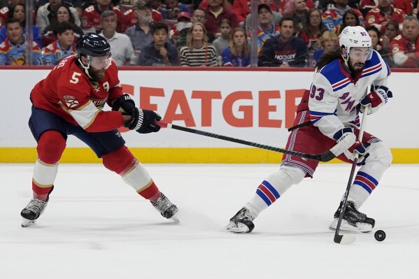 New York Rangers center Mika Zibanejad (93) skates with the puck as Florida Panthers defenseman Aaron Ekblad (5) defends during the first period of Game 6 in the Eastern Conference finals of the NHL hockey Stanley Cup playoffs Saturday, June 1, 2024, in Sunrise, Fla. (AP Photo/Lynne Sladky)