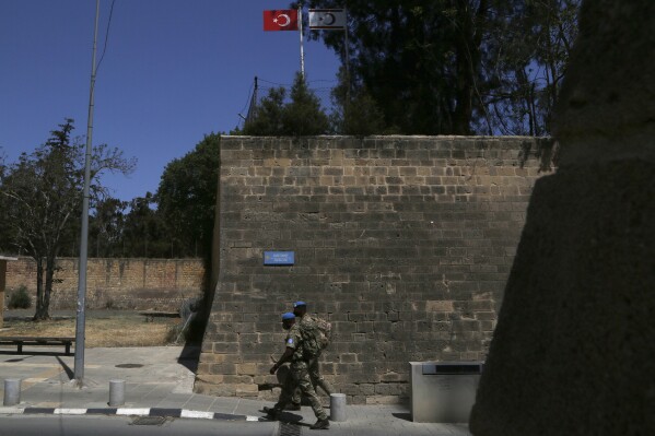 FILE - U.N peacekeepers walk by the Venice wall at the medieval core across the U.N buffer zone, in the divided capital Nicosia, Cyprus, Monday, April 26, 2021. The U.N. Security Council voted unanimously Tuesday, Jan. 30, 2024 to extend the U.N. peacekeeping mission in Cyprus for a year and urged all parties including rival Green Cypriots and Turkish Cypriots to take steps “to de-escalate tensions in and around the buffer zone” dividing the Mediterranean island.(AP Photo/Petros Karadjias, file)