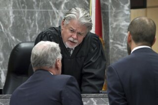 FILE - In this May 22, 2019 file photo, Broward Circuit Judge Dennis Bailey speaks to defense attorney Kevin Kulik in a sidebar discussion during closing arguments in the penalty phase of Pablo Ibar's trial at the Broward County Courthouse in Fort Lauderdale, Fla. Bailey is asking attorneys to get out of bed and put on some clothes when they show up for court hearings on Zoom after complaining to the Weston Bar Association that one male lawyer appeared shirtless and a female attorney was still in bed and under the covers. Broward County's courts are using the video conferencing site for hearings during the coronavirus pandemic. (Amy Beth Bennett/South Florida Sun Sentinel via AP, Pool, File)