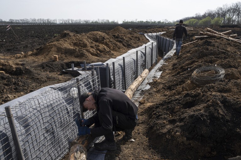 A worker constructs new defensive positions close to the Russian border in Kharkiv region, Ukraine, on Wednesday, April 17, 2024. (AP Photo/Evgeniy Maloletka)