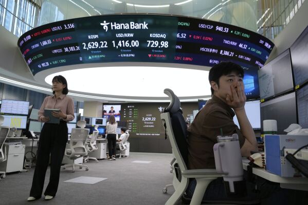 A currency trader watches monitors near a screen showing the Korea Composite Stock Price Index (KOSPI), top center left, and the foreign exchange rate between U.S. dollar and South Korean won, top center, at the foreign exchange dealing room of the KEB Hana Bank headquarters in Seoul, South Korea, Wednesday, May 14, 2025. (AP Photo/Ahn Young-joon)