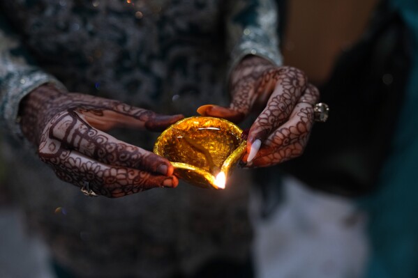 A Hindu woman hold clay-lamp during a ceremony to celebrate Diwali, the festival of lights, at Krishna temple in Lahore, Pakistan, Sunday, Nov. 12, 2023. The Hindu festival of lights, Diwali celebrates the spiritual victory of light over darkness. (AP Photo/K.M. Chaudary)