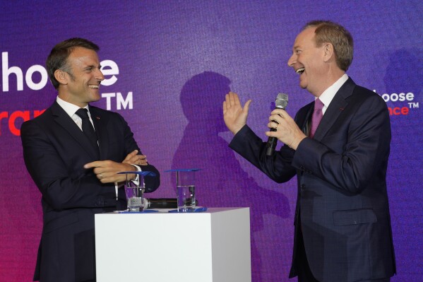 Microsoft CEO Brad Smith, right, speaks to French President Emmanuel Macron at the French Microsoft headquarters in Issy-les-Moulineaux, outside Paris, Monday, May 13, 2024. Microsoft, which has been present in France for 41 years, is announcing a 4 billion euro investment this year, the largest to date in the country, to support French growth in the new artificial intelligence economy. (AP Photo/Thibault Camus, Pool)