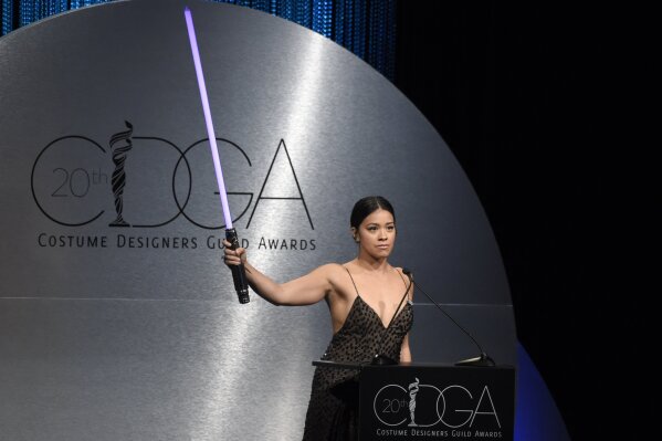 
              Gina Rodriguez raises a lightsaber as she introduces Mark Hamill at the 20th annual Costume Designers Guild Awards at The Beverly Hilton hotel on Tuesday, Feb. 20, 2018, in Beverly Hills, Calif. (Photo by Chris Pizzello/Invision/AP)
            