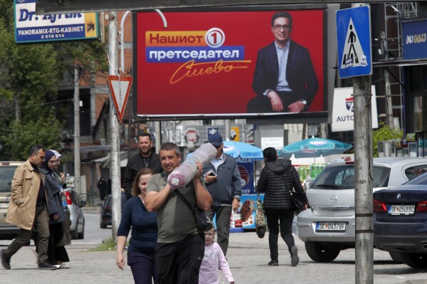 People walk past election poster of Stevo Pendarovski, incumbent President and a presidential candidate backed by the ruling social democrats (SDSM), in a street in Skopje, North Macedonia, on Monday April 22, 2024. Voters go to the polls in North Macedonia on Wednesday April 24 for the first round of presidential elections, the seventh such election since the Balkan country gained independence from the former Yugoslavia in 1991, where seven candidates are vying for the largely ceremonial position. (AP Photo/Boris Grdanoski)