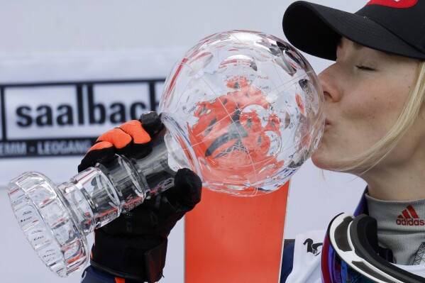United States' Mikaela Shiffrin kisses the trophy for the alpine ski, women's World Cup slalom discipline, in Saalbach, Austria, Saturday, March 16, 2024. (AP Photo/Alessandro Trovati)