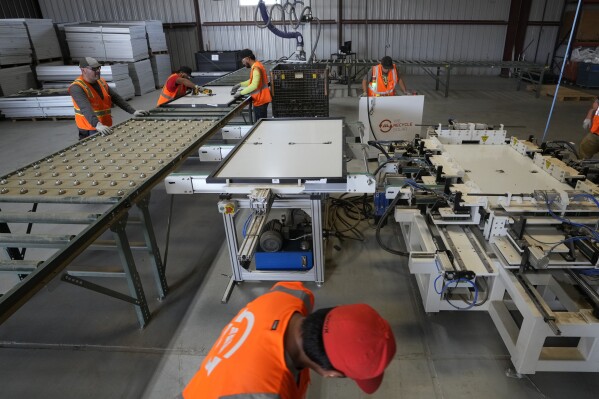 Workers take apart solar panels as they begin the recycling process at We Recycle Solar on Tuesday, June 6, 2023, in Yuma, Ariz. (AP Photo/Gregory Bull)