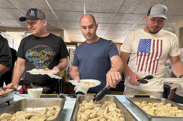 FILE - Maksym Bunchukov, Andrii Hryshchuk and Ivan Sakivskyi help themselves to perogies at a lunch hosted Monday, July 17, 2023, by the Ukrainian Cultural Institute in Dickinson, North Dakota. The North Dakota Petroleum Council's Bakken Global Recruitment of Oilfield Workers program placed about 60 Ukrainians with 16 employers throughout western North Dakota from July to November 2023, Council President Ron Ness said. The group shelved the program due to lack of demand from companies, he said. (AP Photo/Jack Dura, File)