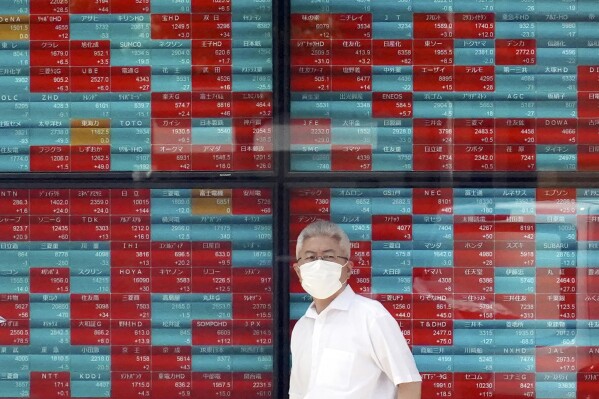 FILE - A person stands in front of an electronic stock board showing Japan's Nikkei 225 index at a securities firm Monday, Sept. 11, 2023, in Tokyo. Asian shares mostly sank Tuesday, Sept. 26, over worries about a possible U.S. government shutdown and the troubled Chinese economy.(AP Photo/Eugene Hoshiko, File)