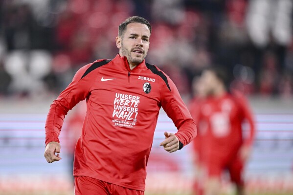 Freiburg's Christian Günter, wearing a warm-up shirt with the inscription 'Our values our choice! - Together for Democracy', loosens up before the Bundesliga soccer match between SC Freiburg and Werder Bremen at Europa-Park Stadium in Freiburg, Germany, Friday Feb. 21, 2025. (Harry Langer/dpa via AP)
