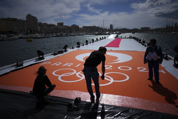 Workers prepare for the arrival of the Olympic flame in the Old Port of Marseille in southern France, Tuesday, May 7, 2024. The Olympic torch will finally enter France when it reaches the southern seaport of Marseille on Wednesday. (AP Photo/Daniel Cole)