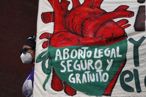 FILE - A woman holds a banner reading in Spanish, 