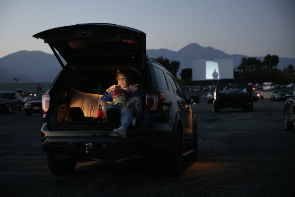 Serena Benavidez looks at her smartphone while waiting for a movie to start at Mission Tiki drive-in theater in Montclair, Calif., Thursday, May 28, 2020. California moved to further relax its coronavirus restrictions and help the battered economy. Flea markets, swap meets and drive-in movie theaters can resume operations. (AP Photo/Jae C. Hong)