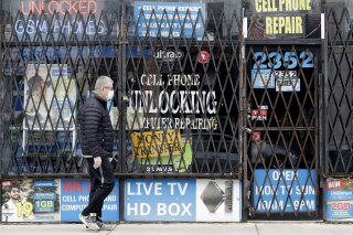 FILE - In a  April 30, 2020 file photo, a man walks by a closed store during the COVID-19 in Chicago. Layoffs are declining and hiring is slowly picking up, yet it's not really clear where the job market goes next.  (AP Photo/Nam Y. Huh, File)